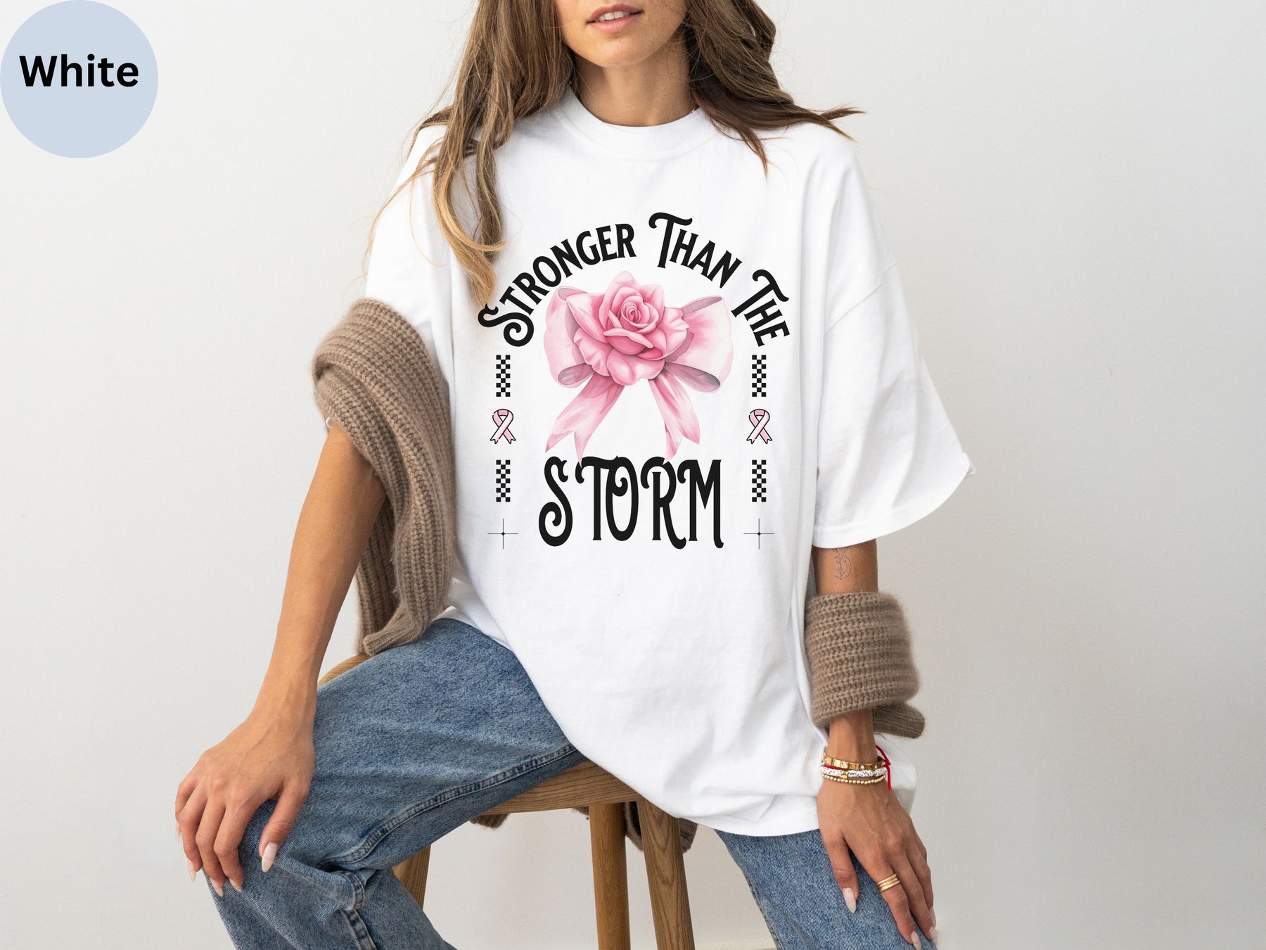 a woman sitting on a stool wearing a t - shirt with a pink rose on