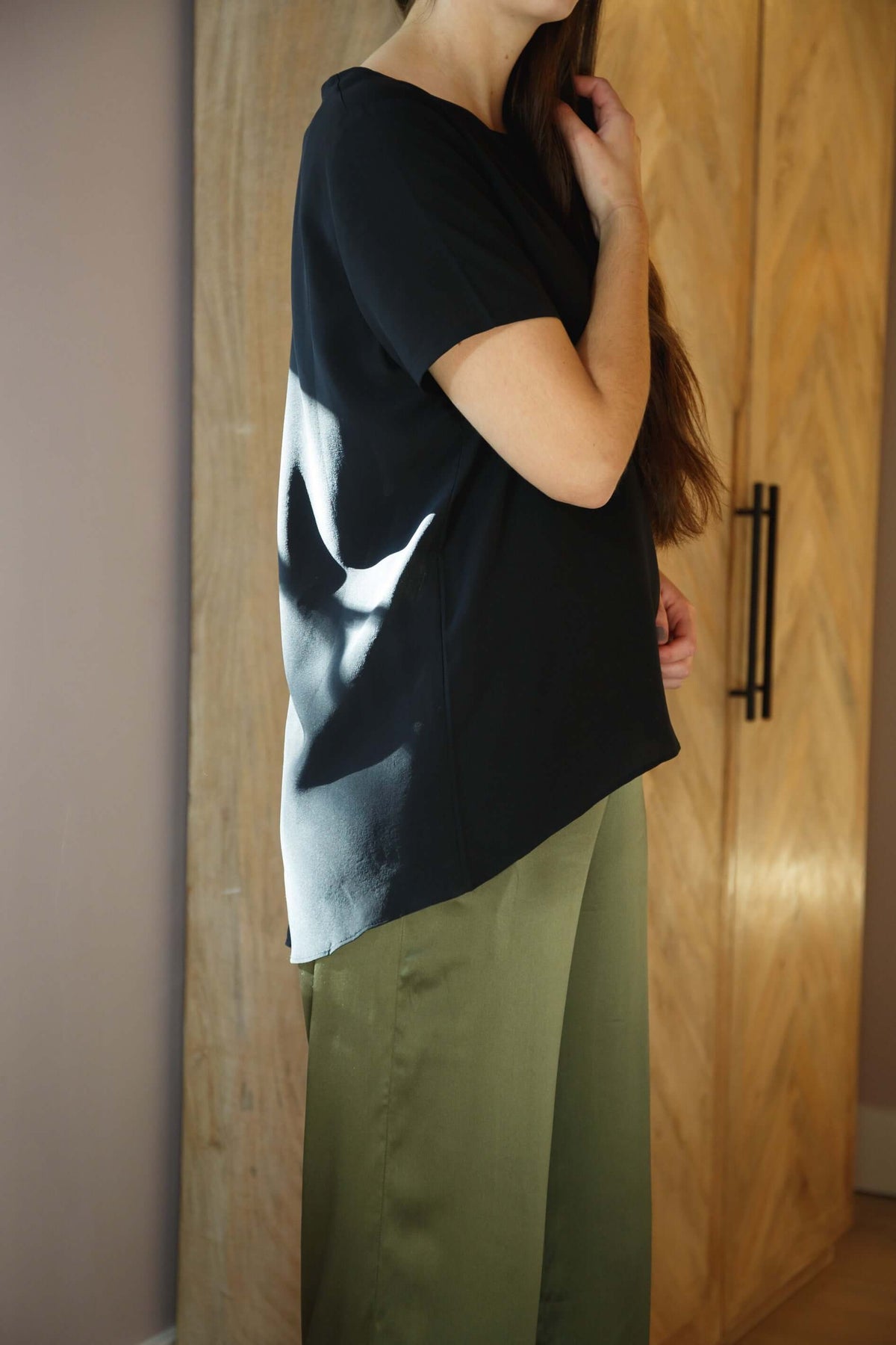 Woman wearing black silk tee top with relaxed fit and high low hem