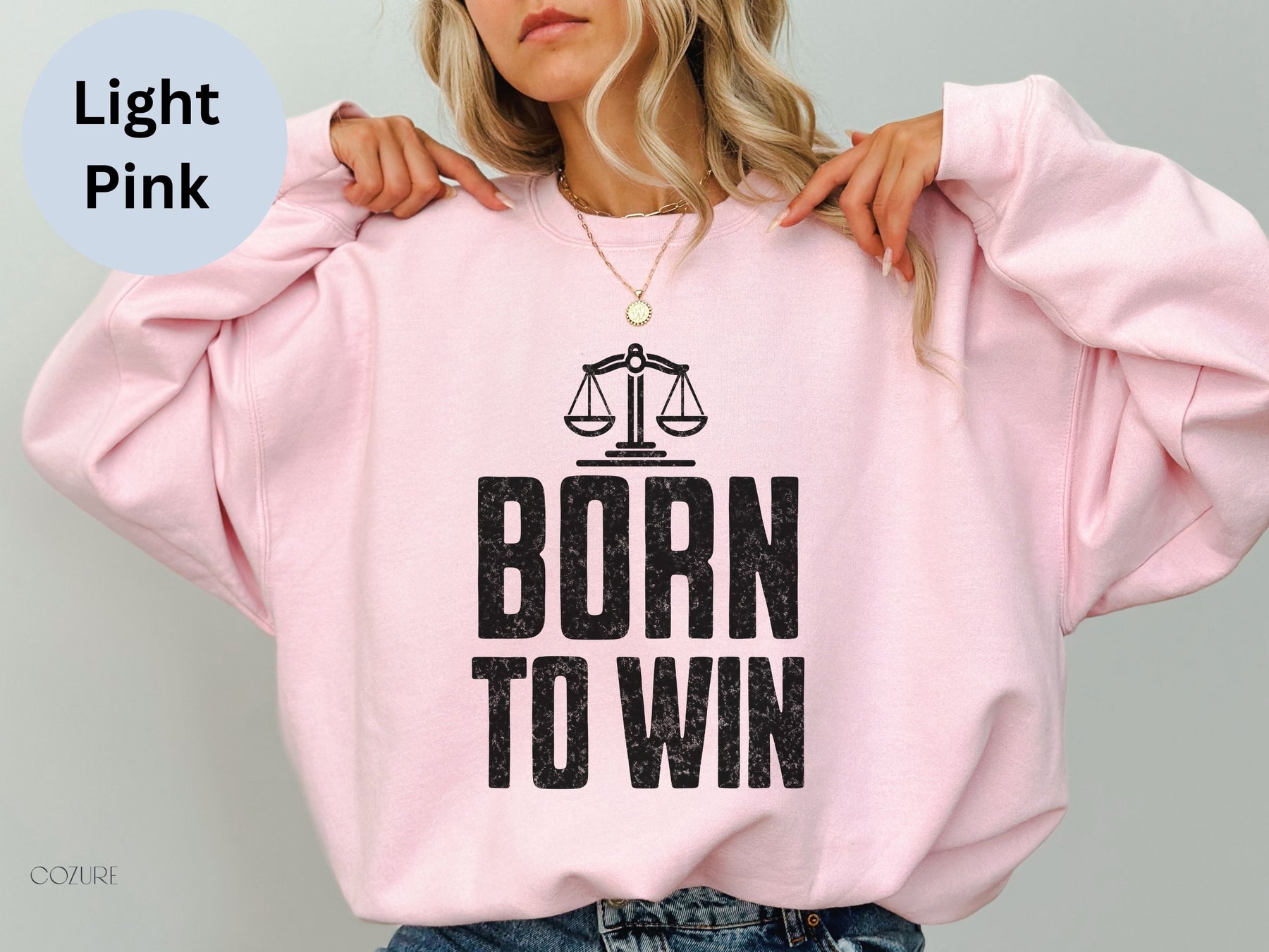 a woman wearing a pink sweatshirt with the words born to win printed on it