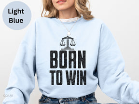 a woman wearing a light blue sweatshirt with the words born to win printed on it