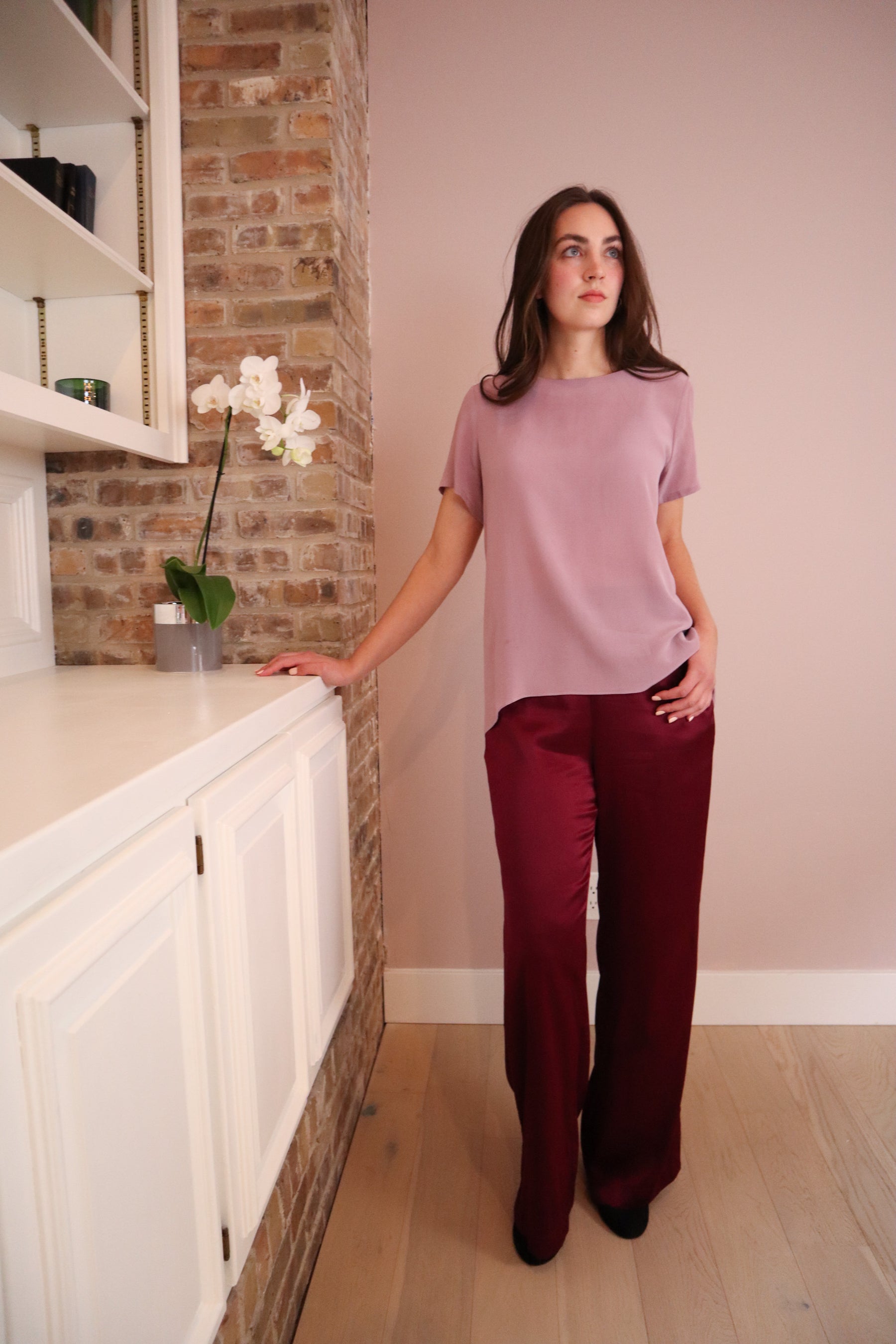 Woman wearing wine colored silk pants paired with a lilac silk top