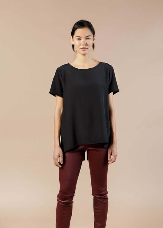  Woman wearing black silk tee top with relaxed fit and high low hem showing front view