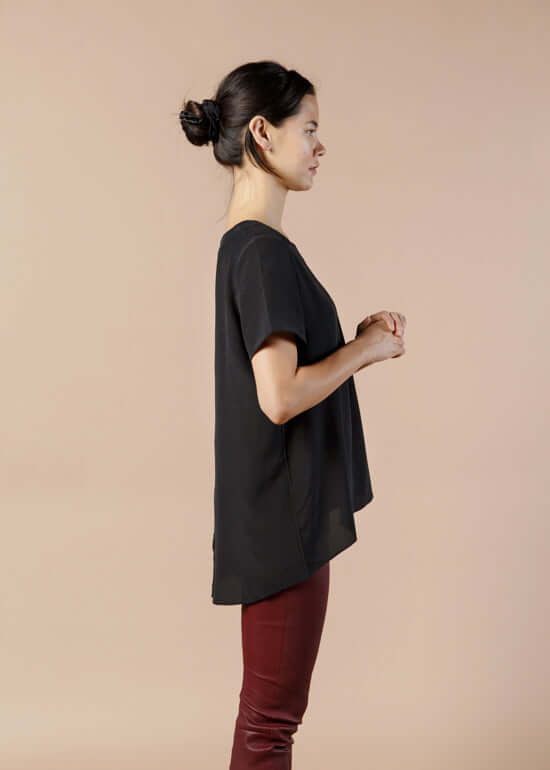 Woman wearing black silk tee top with relaxed fit and high low hem showing side view