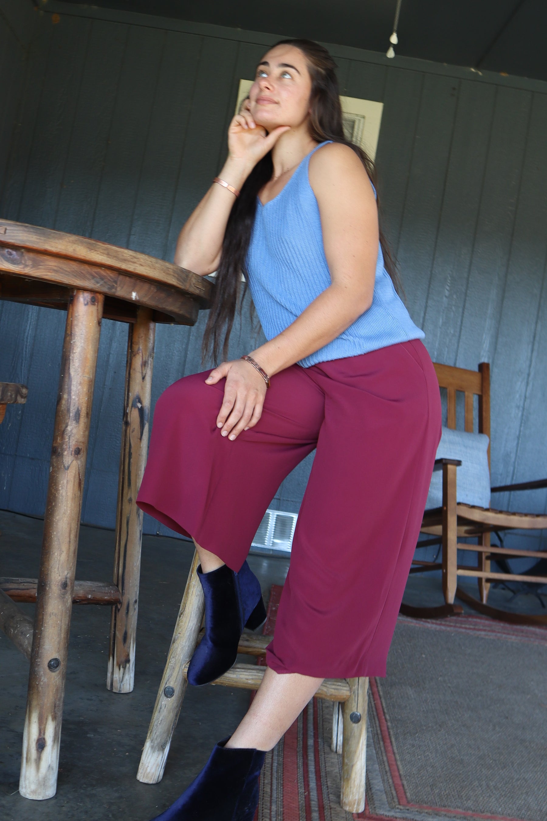 Woman Sitting and Wearing sustainable red silk culottes ankle pants with wide leg