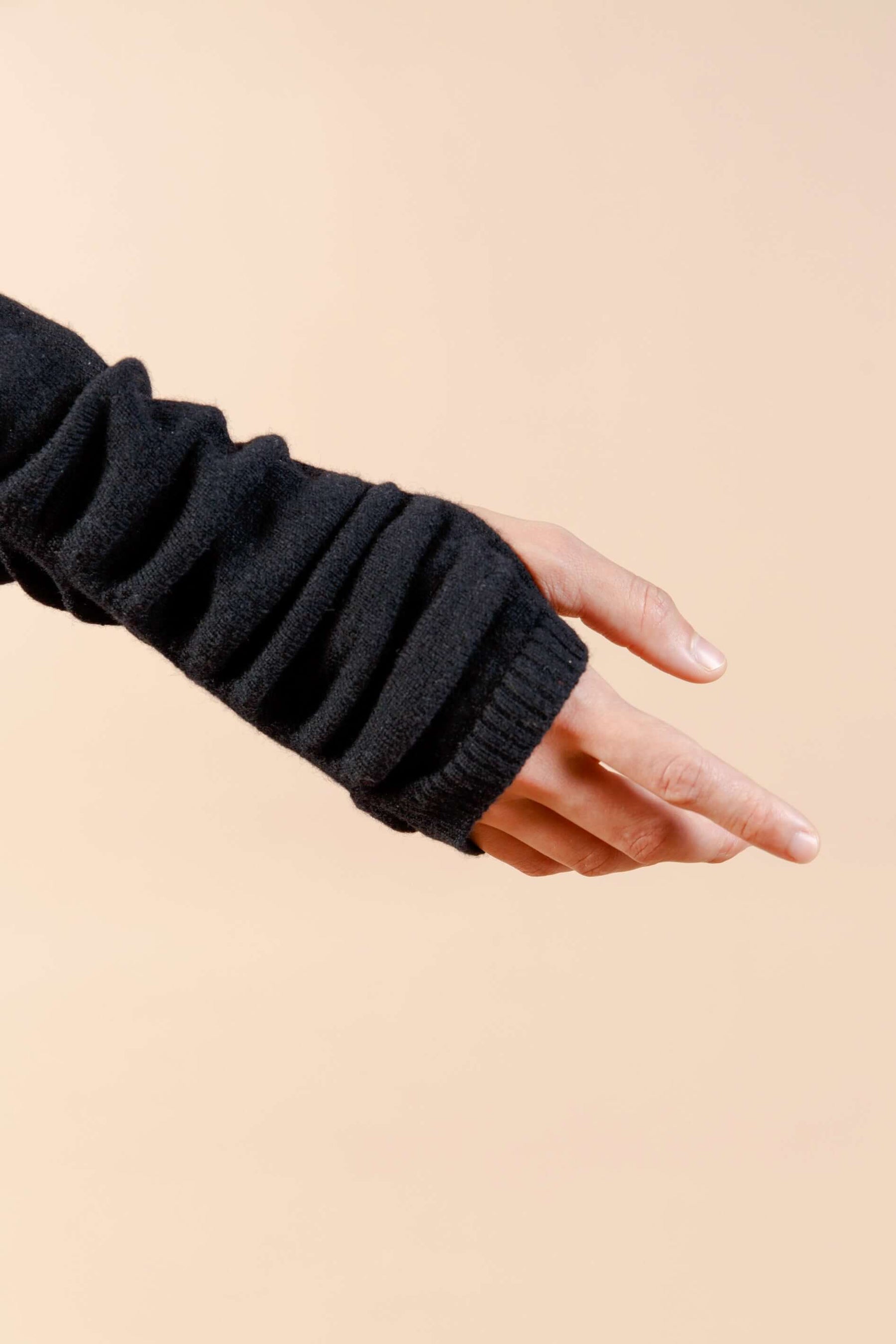 Close up of thumbholes at wrist and sleeve of black cashmere sweater dress