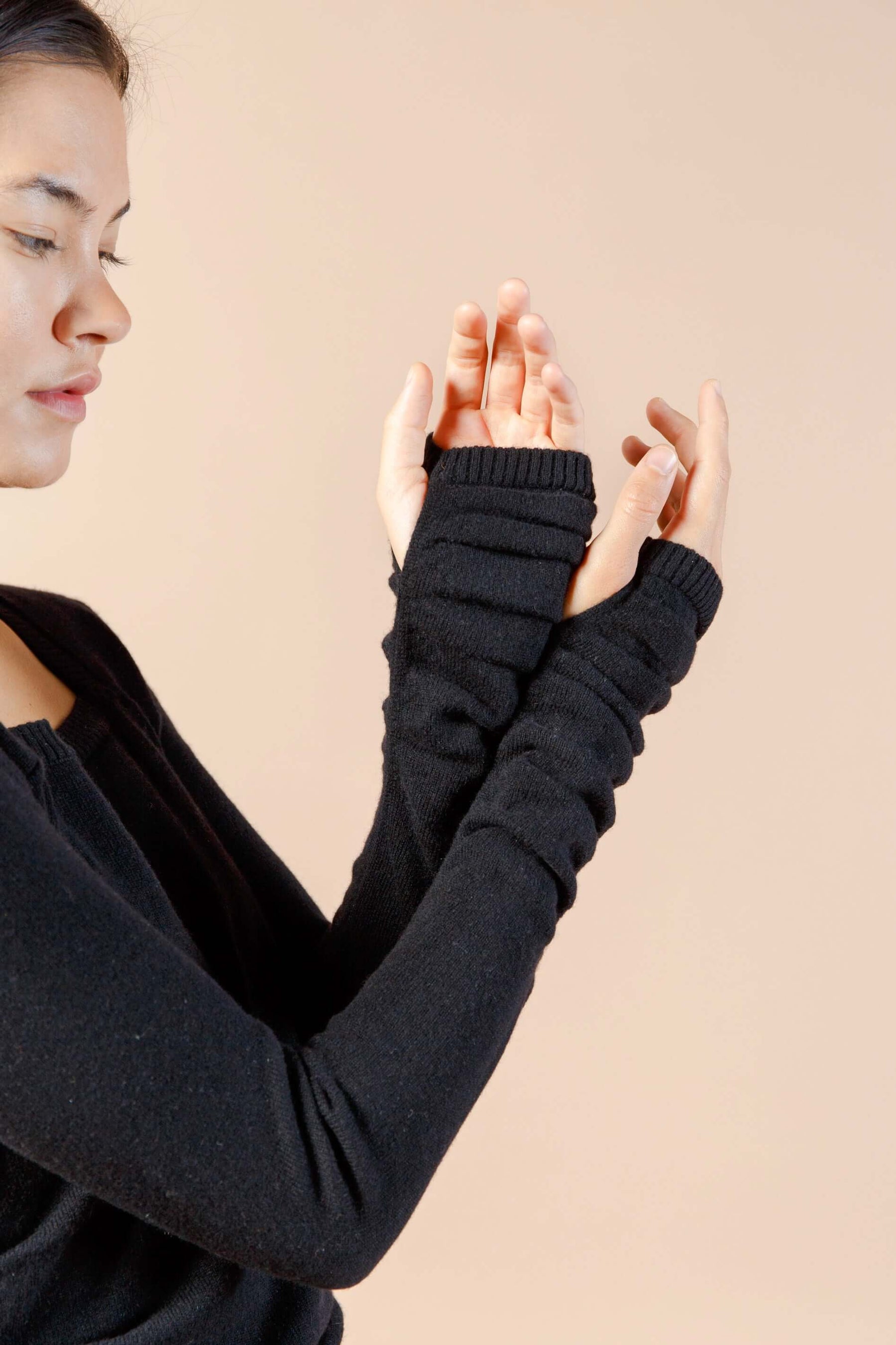 Woman wearing long sleeve black sexy cashmere sweater dress close up of thumbholes at wrist