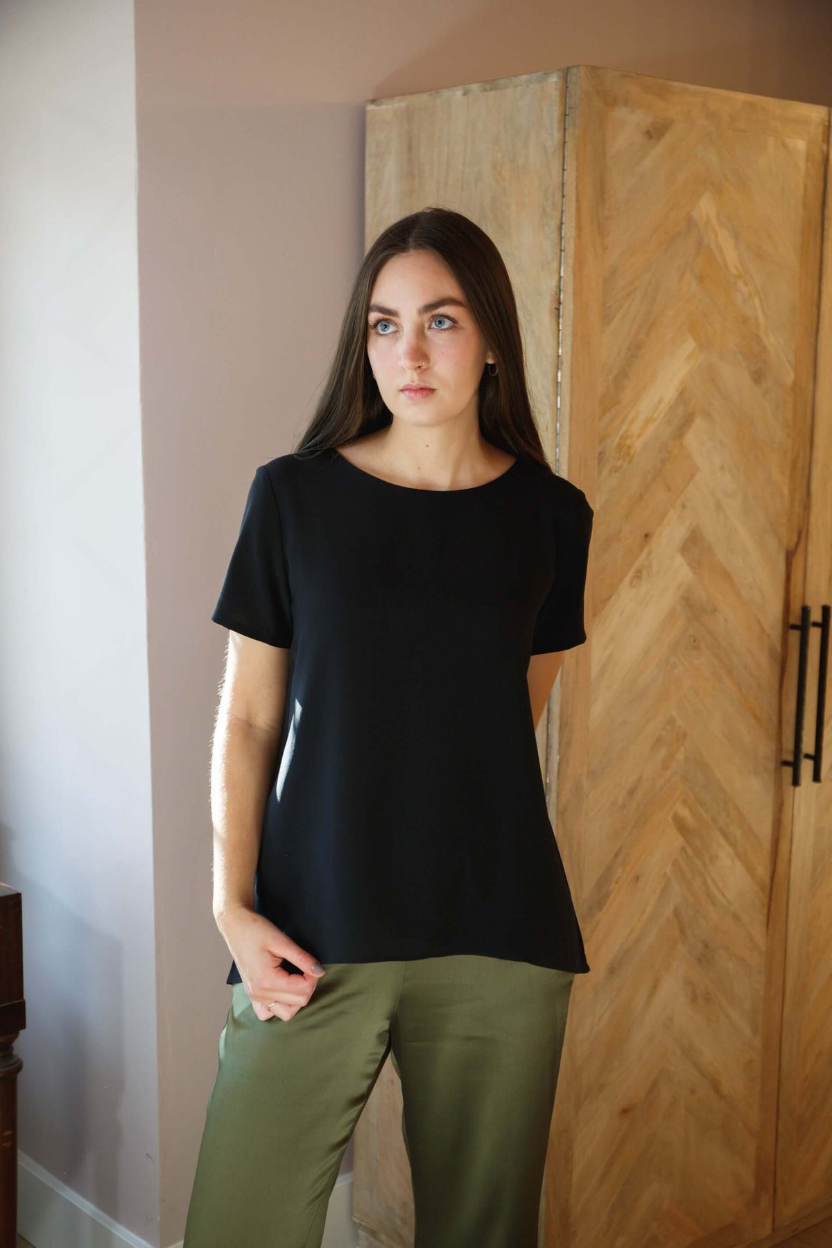 Woman wearing black silk tee top with relaxed fit and high low hem